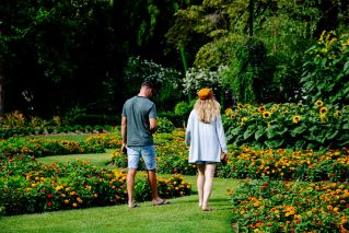 A man and a woman walking through a colorful botanical garden with lush flowers.